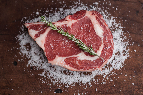Rohes Steak mit Salz und Rosmarin auf Holztisch